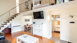 A modern interior with a staircase, dining area, kitchen, and a TV mounted on the wall.