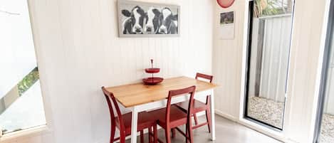 En matplats med ett träbord och röda stolar, en inramad tavla på väggen och ett fönster med utsikt över omgivningen.