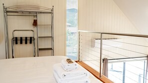 A hotel room with a bed, a metal rack with towels, and a view of the outdoors. - ALLAMBIE COTTAGES - VILLA 1: Bright (Bright)