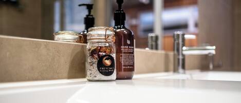 A bathroom sink with a jar of hand wash soap and a bottle of hand wash cream.