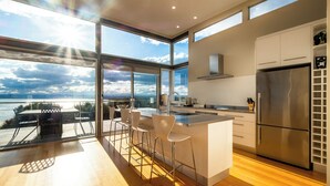 Una cocina moderna con una isla grande, taburetes de bar y vistas al mar.