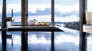 Una cocina con un amplio ventanal que da a un cuerpo de agua y nubes.