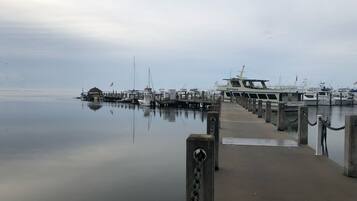 Un port de plaisance avec des bateaux amarrés à des quais en bois, un ciel dégagé et une eau calme.