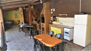 A rustic kitchen with a brick oven, a refrigerator, and a dining area with tables and chairs. - Leisure and Rest for any day (Guararema)