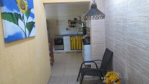 A narrow hallway with a kitchen in the background, a black chair, and a hanging light fixture. - Leisure and Rest for any day (Guararema)