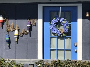 Eine blaue Tür mit einem violetten Kranz, eine blau-weiße Wand und dekorative Laternen.