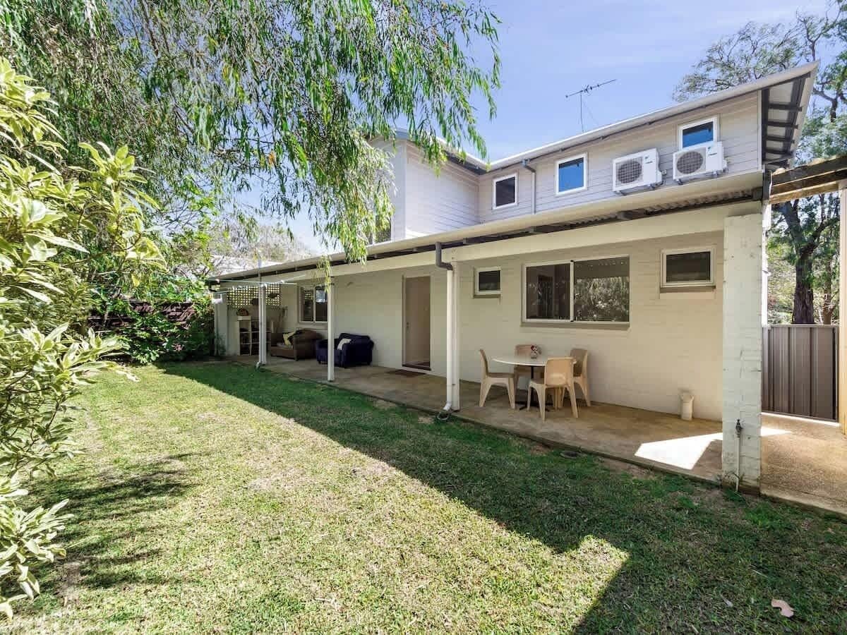 A residential property with a covered patio, a lawn, and a small garden area.