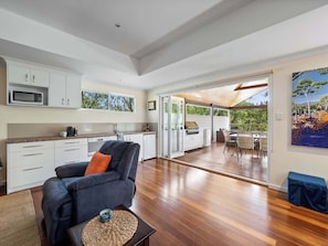 A spacious living area with a sofa, a coffee table, and a kitchen area with cabinets and a microwave.