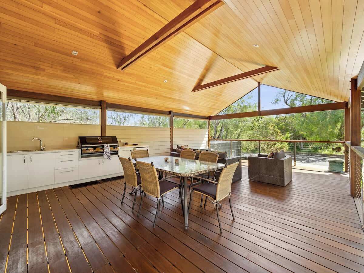 An outdoor covered patio with a dining table and chairs, a grill, and a seating area.