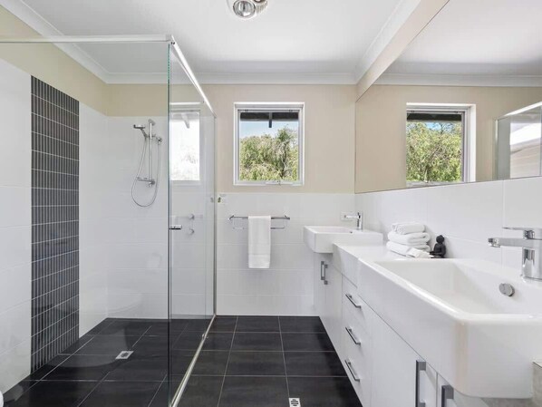 A modern bathroom with a glass shower enclosure, a white sink, and a large mirror.