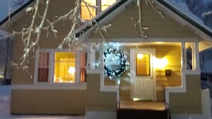 A two-story house with a snow-covered roof and front porch.