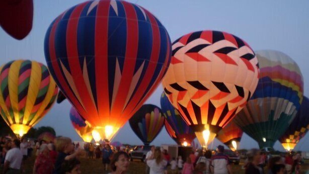 A group of hot air balloons at dusk.