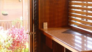 Un espacio con barra de madera, una barra, un taburete y una ventana con persianas.