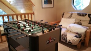 A foosball table with the brand 'PYTHON' in a room with a wooden ceiling, a window with a view of trees, and a sofa with patterned cushions. - Pinecrestarearentals #8 Getaway Fall/labor day 3rd night free just Book 2nights. (Cold Springs)