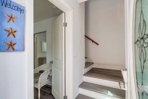 A staircase with a wooden handrail and a glass door leading to a room with a wicker chair.