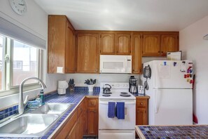 A kitchen with wooden cabinets, a microwave, a stove, a sink, and a refrigerator.
