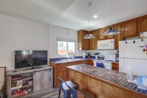 A modern kitchen with wooden cabinets, a large island, and a built-in TV. - New-A/C! Between Beach and Bay, garage/bikes/pets! (San Diego)