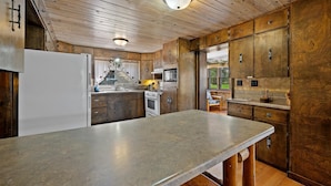 A kitchen with wooden cabinets, a granite countertop, and a stainless steel refrigerator.