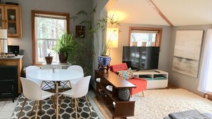 Un salon confortable avec un coin repas, un téléviseur et une grande fenêtre.