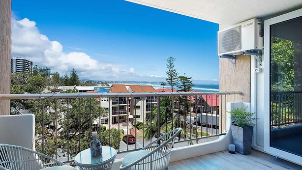 A balcony with a view of the ocean, a statue, and a Mitsubishi air conditioning unit.