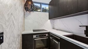 A modern kitchen with a herringbone tile backsplash, a built-in oven, and a window above the sink.