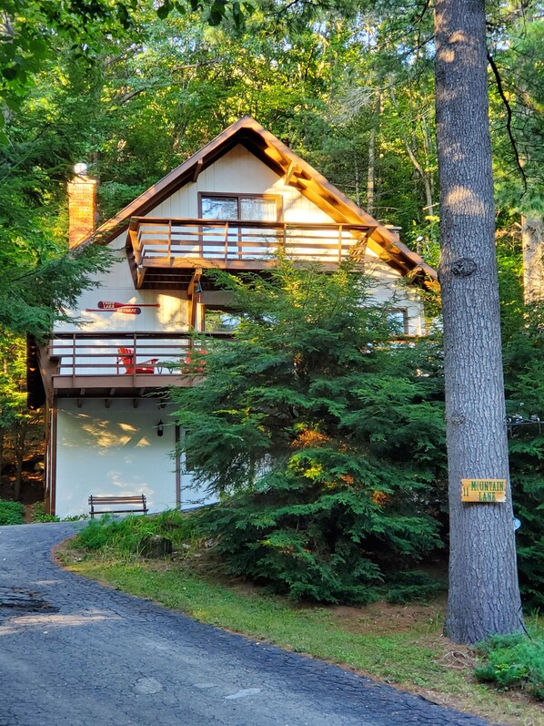 Una cabaña de dos pisos con fachada de madera, un balcón y un cartel que dice 'Thrifty Lake Retreat'.