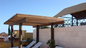 A covered outdoor seating area with white lounge chairs and a pergola structure. - Charming Mexican Style Condo with a fantastic location (Playa del Carmen)