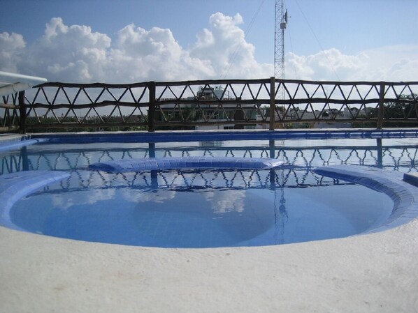 Une piscine entourée d’une clôture en métal, sous un ciel dégagé.