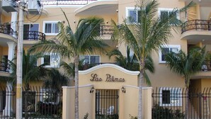 A hotel entrance with a sign reading "Las Palmas," surrounded by palm trees and a gated entrance. - Charming Mexican Style Condo with a fantastic location (Playa del Carmen)
