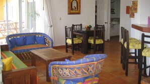 A dining area with a round table and chairs, a sofa, and a wooden coffee table. - Charming Mexican Style Condo with a fantastic location (Playa del Carmen)