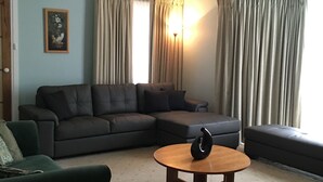 A living room with a sectional sofa, a round coffee table, and a green armchair. - Southern Escape - A Family Friendly Home 3 minute walk to  the Beach  (VICTOR HARBOR)
