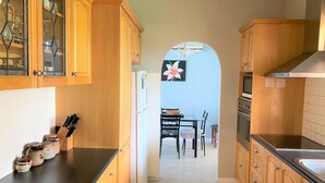 A kitchen with wooden cabinets, a refrigerator, a dining table with chairs, and a tiled floor. - Southern Escape - A Family Friendly Home 3 minute walk to  the Beach  (VICTOR HARBOR)