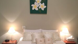 A neatly made bed with a floral painting above it, two bedside lamps, and a clock on the nightstand. - Southern Escape - A Family Friendly Home 3 minute walk to  the Beach  (VICTOR HARBOR)
