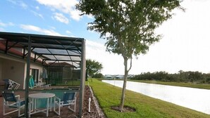 A covered outdoor area with a pool, chairs, and a table. - A gorgeous lake sunset view villa in a gated High Grove resort near Disney (Clermont)