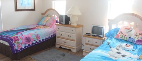 Une chambre avec deux lits, une commode, une lampe et un téléviseur.