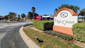 A sign for High Grove with a clear road and palm trees in the background. - A gorgeous lake sunset view villa in a gated High Grove resort near Disney (Clermont)