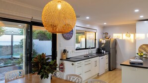 A modern kitchen with white cabinets, a large island, and a hanging light fixture. - ABSOLUTE BEACHFRONT - Smooth Sailing Yorke Peninsula (Coobowie)