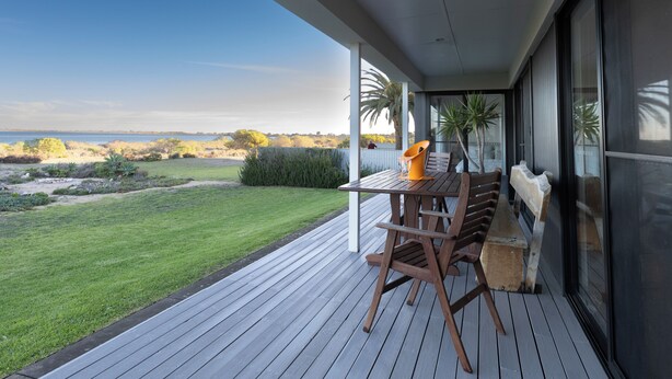 A wooden deck with a table and benches overlooking a grassy area and the sea. - ABSOLUTE BEACHFRONT - Smooth Sailing Yorke Peninsula (Coobowie)