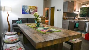 Una cocina moderna con encimeras de madera, una mesa de comedor con un mantel individual de colores y un sofá gris al fondo.