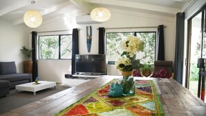 Una sala de estar moderna con una mesa de centro de madera, un sofá, un televisor de pantalla plana y una alfombra colorida.