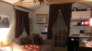 A cozy bedroom with a large bed, a desk, and a kitchenette.