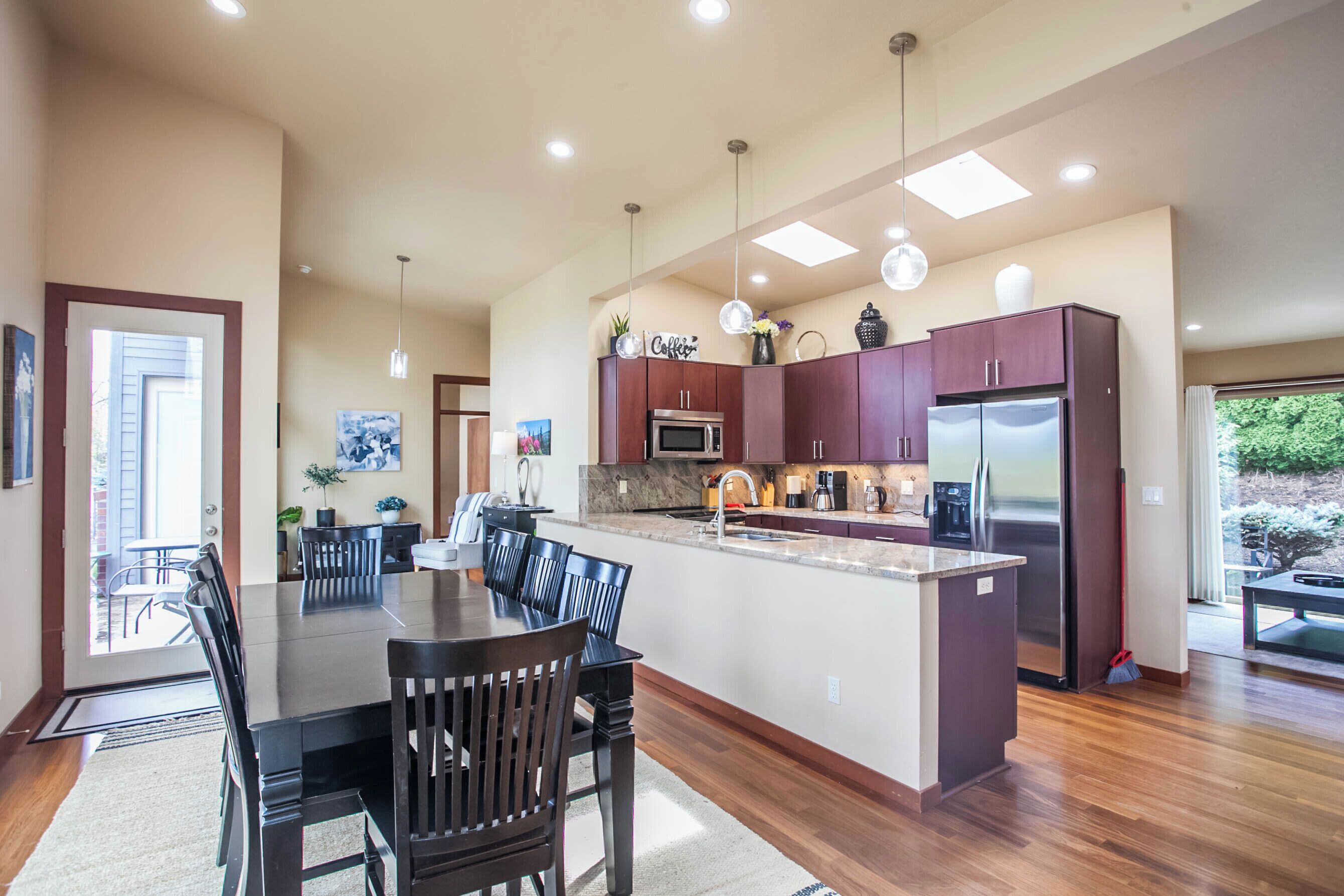 A modern kitchen with dark wood cabinets, stainless steel appliances, and pendant lighting.