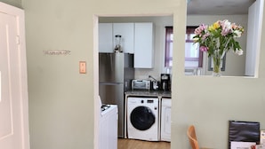 Une cuisine compacte équipée d’un lave-linge, d’une machine à café et d’un grille-pain.