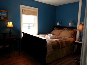 A bedroom with a bed, two bedside lamps, a window with a beige blind, a wooden chair, and a small table. - Maria's JP Rental - Boston Duplex in Popular Jamaica Plain "JP" area (Boston)