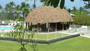 A covered outdoor seating area with a pool and lounge chairs.