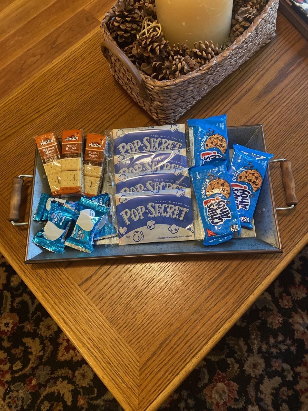 A tray with various snacks and a candle on a wooden table.