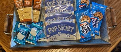 A tray with various snacks and a candle on a wooden table.