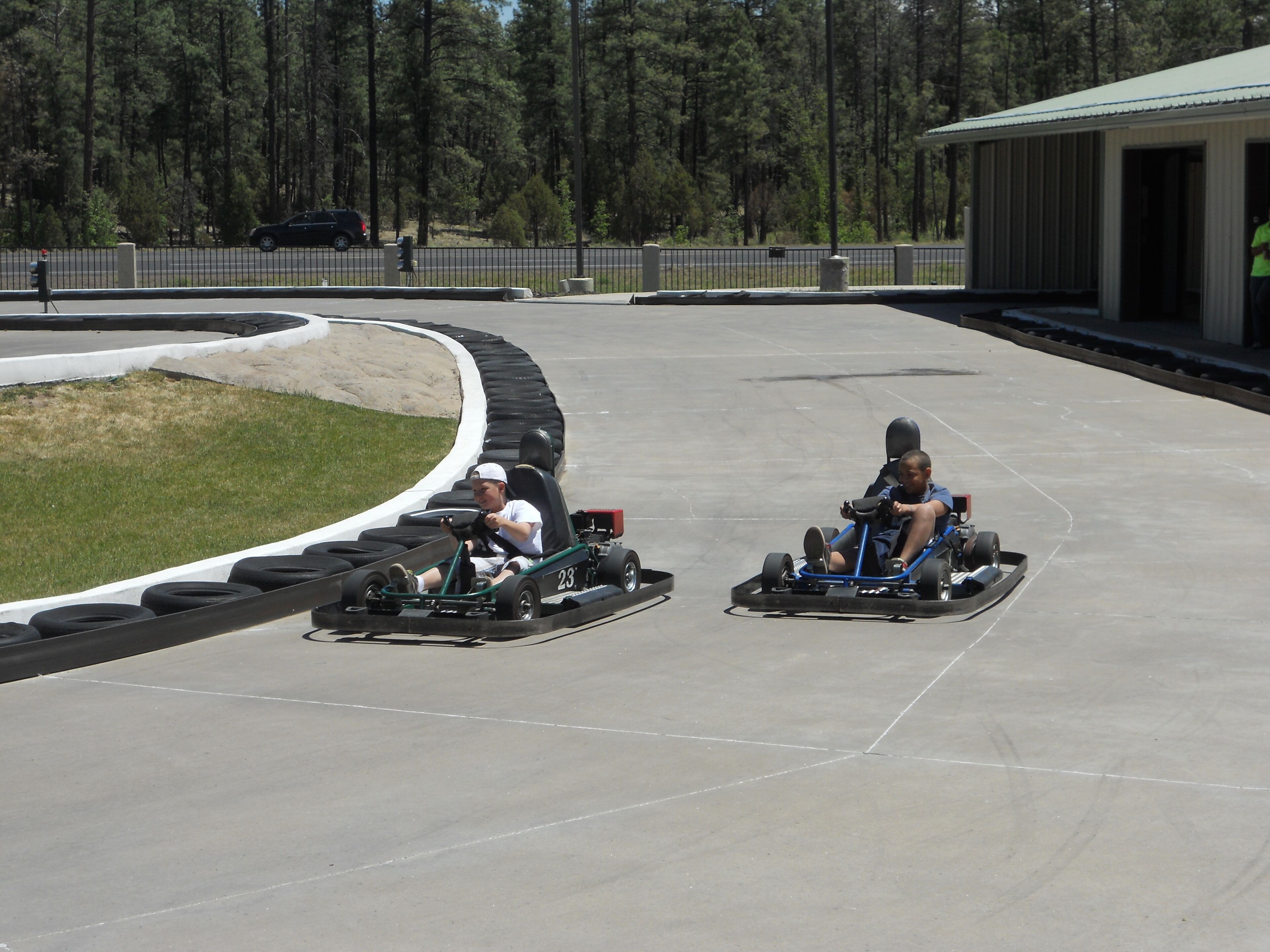 A go-kart track with two go-karts and a person in a yellow shirt.