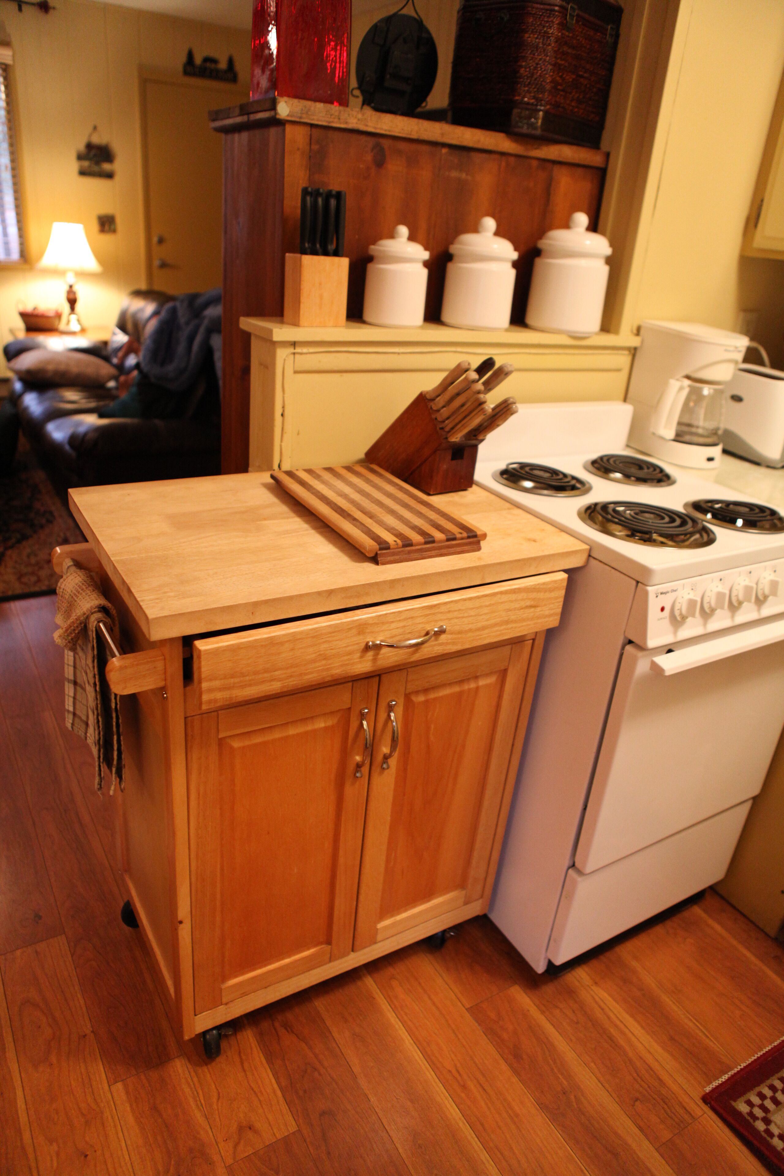 Une cuisine de taille réduite, dotée d’un plan de travail en bois, d’une cuisinière et d’un placard.