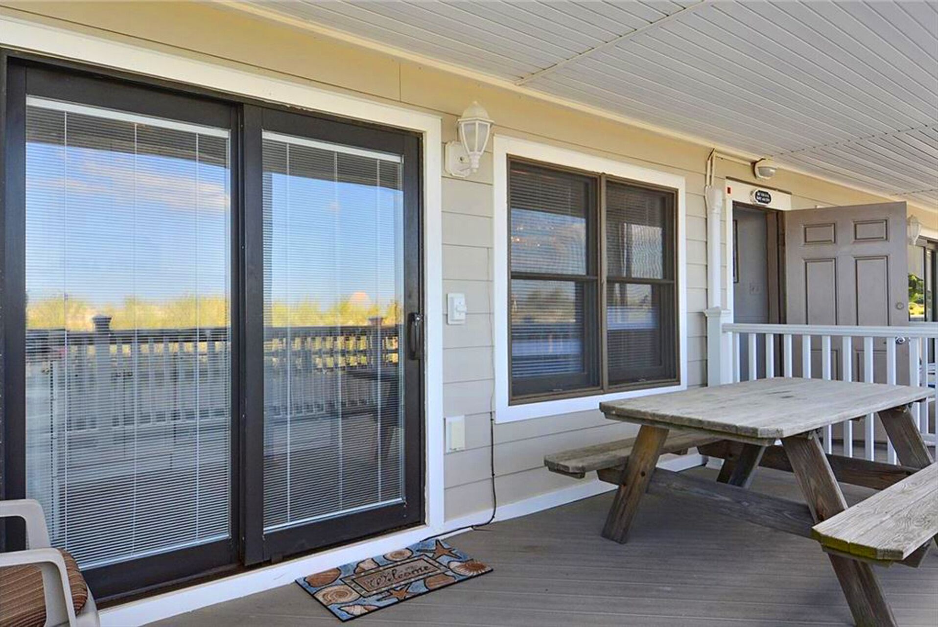 A covered porch with a wooden bench and a welcome mat.